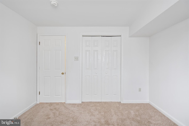 unfurnished bedroom featuring light carpet and baseboards