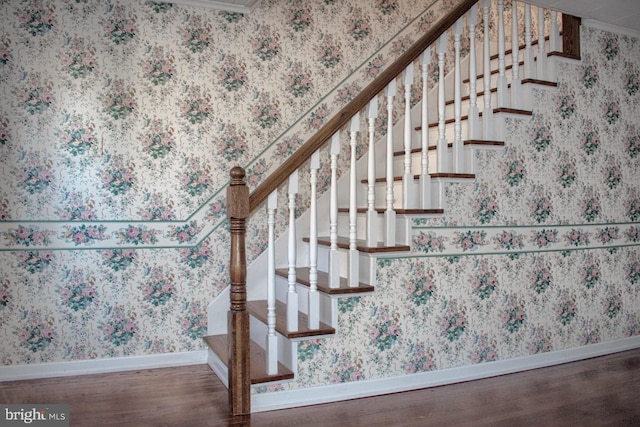 stairs with wood-type flooring and crown molding