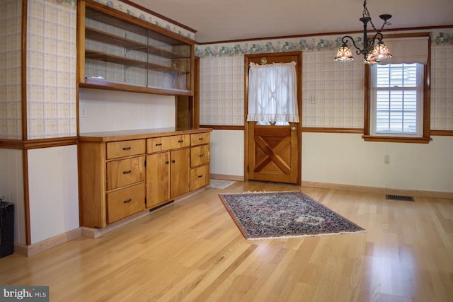 interior space featuring ornamental molding, light hardwood / wood-style floors, and a notable chandelier