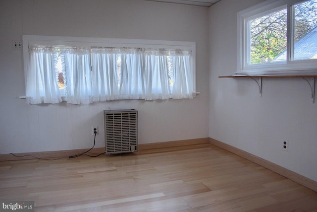 empty room with light hardwood / wood-style floors and heating unit