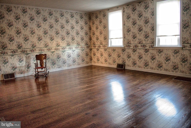 unfurnished room with ornamental molding, dark wood-type flooring, and a healthy amount of sunlight