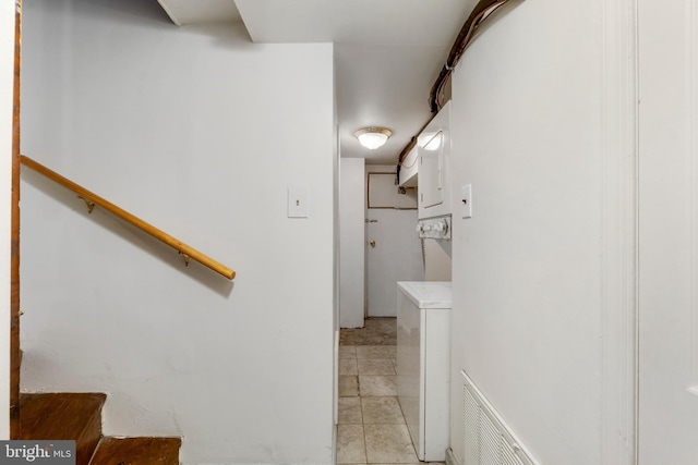 stairs featuring stacked washing maching and dryer