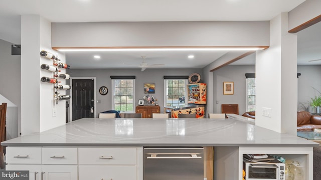 kitchen with white cabinetry, light stone counters, and ceiling fan