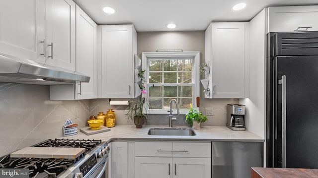 kitchen featuring sink, premium appliances, tasteful backsplash, light stone counters, and white cabinets