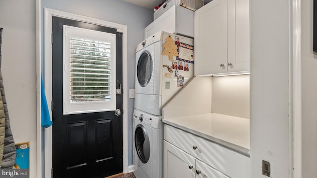 laundry room featuring cabinets and stacked washer / dryer