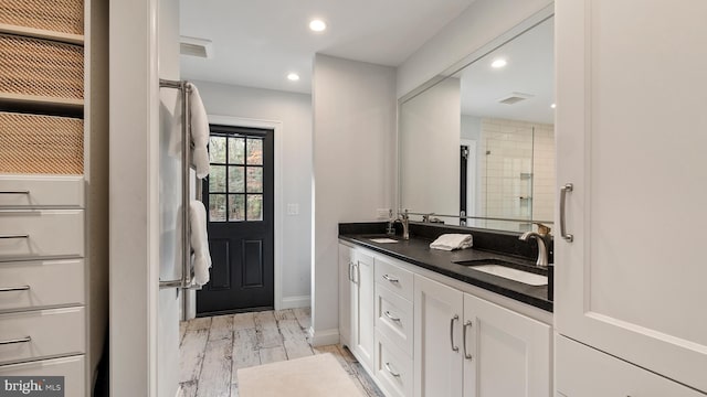 bathroom featuring tiled shower, wood-type flooring, and vanity