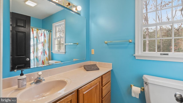 bathroom featuring vanity, a healthy amount of sunlight, and toilet