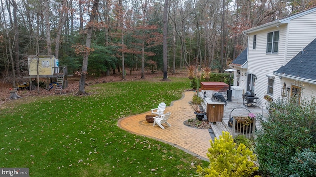 view of yard featuring a fire pit, a patio area, a storage shed, and a hot tub