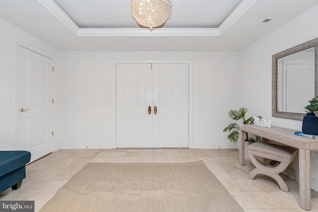 tiled foyer entrance with a notable chandelier, ornamental molding, and a tray ceiling