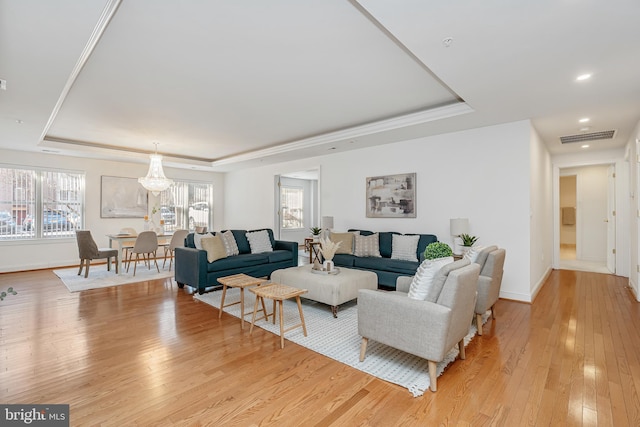 living room with light hardwood / wood-style flooring and a tray ceiling