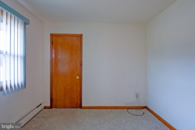 spare room with light colored carpet, plenty of natural light, and a baseboard heating unit