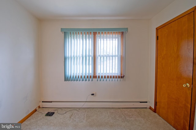 carpeted empty room with a baseboard heating unit