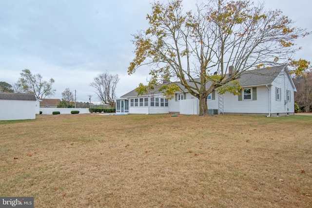 rear view of house featuring a lawn and a sunroom