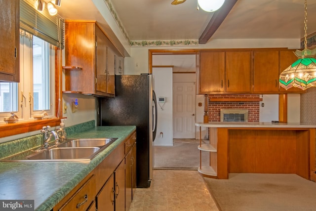 kitchen featuring sink, a brick fireplace, kitchen peninsula, stainless steel fridge, and light carpet