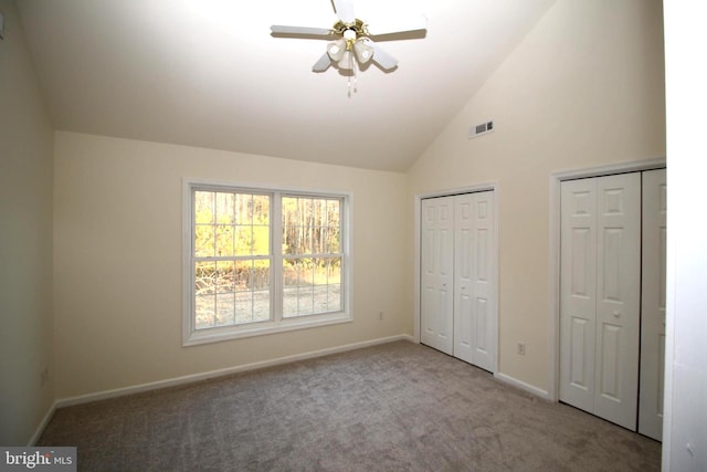 unfurnished bedroom featuring ceiling fan, high vaulted ceiling, light colored carpet, and two closets