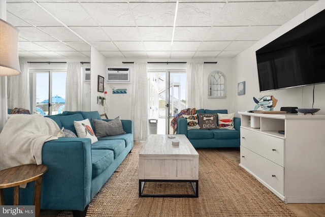 living room featuring a paneled ceiling and a wall mounted AC