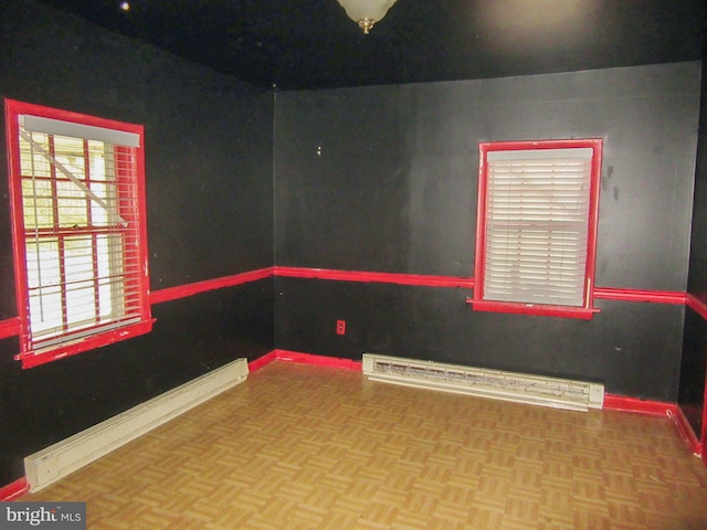 unfurnished room featuring parquet flooring and a baseboard heating unit