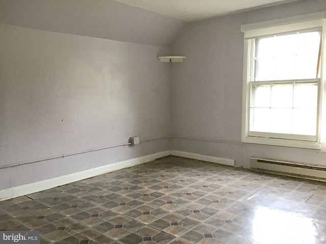 spare room featuring vaulted ceiling and a baseboard heating unit