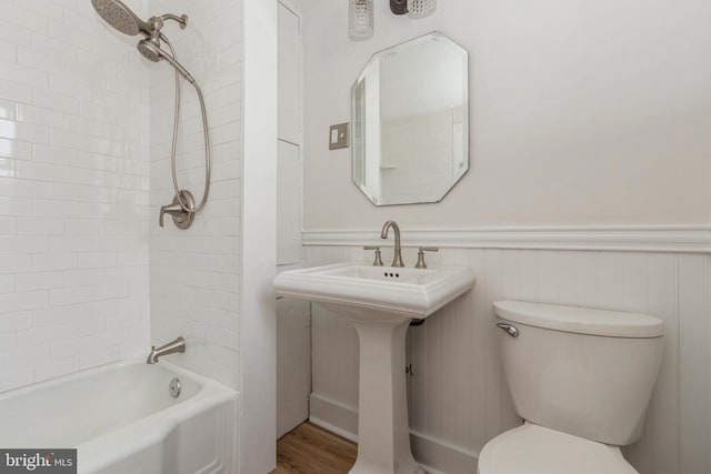 bathroom featuring wood-type flooring, toilet, and tiled shower / bath