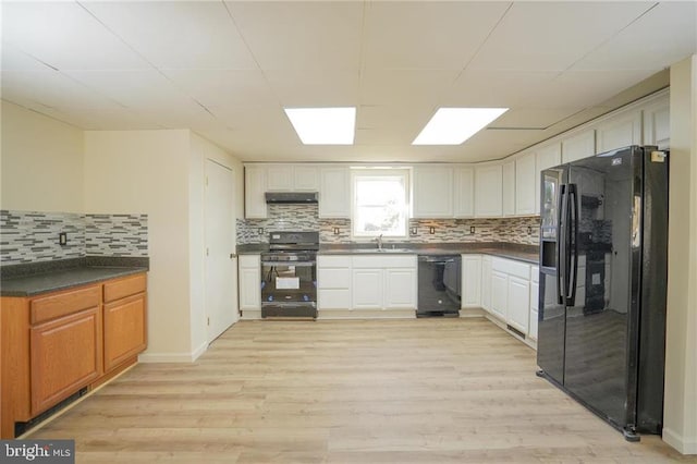 kitchen with decorative backsplash, light wood-type flooring, sink, black appliances, and white cabinetry