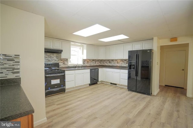 kitchen featuring tasteful backsplash, white cabinetry, black appliances, and light wood-type flooring