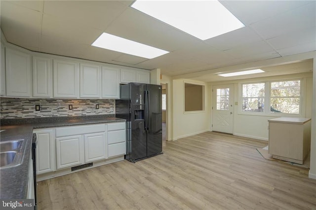 kitchen with white cabinets, light wood-type flooring, and black refrigerator with ice dispenser