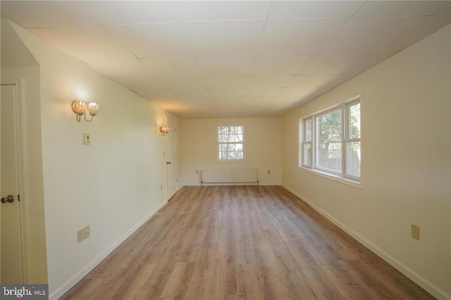 unfurnished room featuring light hardwood / wood-style floors and radiator heating unit