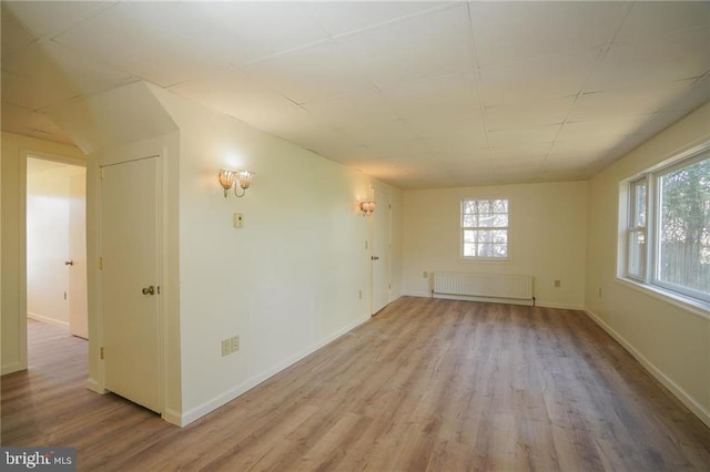 unfurnished room with light wood-type flooring and radiator heating unit