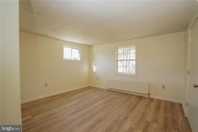 spare room featuring radiator heating unit and light hardwood / wood-style floors