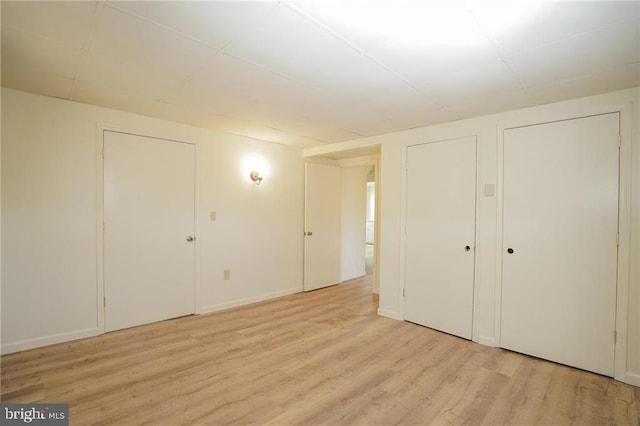 unfurnished bedroom with light hardwood / wood-style floors and two closets