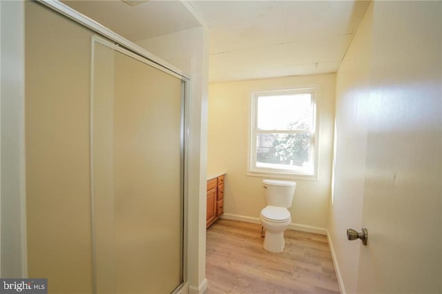 bathroom with wood-type flooring, vanity, toilet, and a shower with shower door