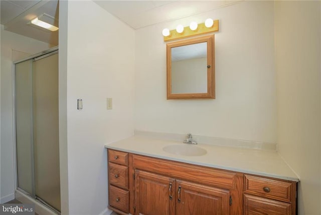 bathroom featuring a shower with door and vanity