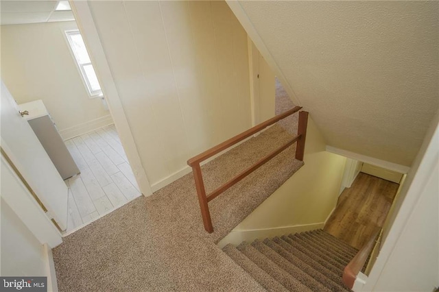 stairway with hardwood / wood-style floors and a textured ceiling