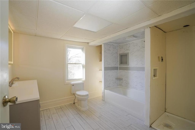 bathroom featuring a paneled ceiling, a tub to relax in, vanity, hardwood / wood-style floors, and toilet