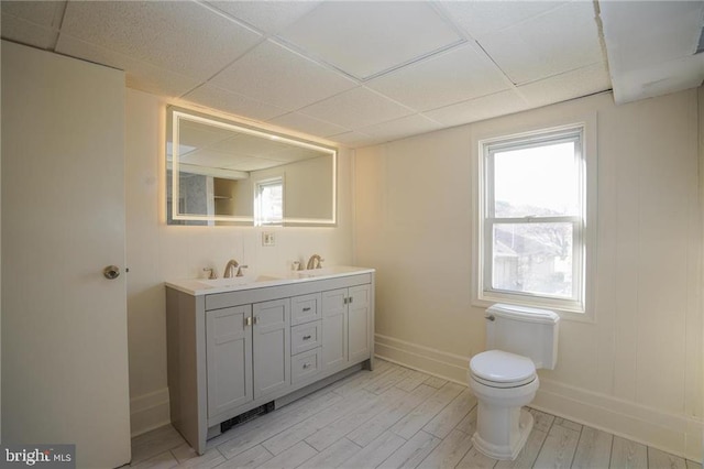 bathroom featuring hardwood / wood-style floors, vanity, a healthy amount of sunlight, and a drop ceiling