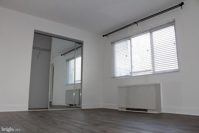 unfurnished room featuring radiator, dark hardwood / wood-style floors, and a wealth of natural light