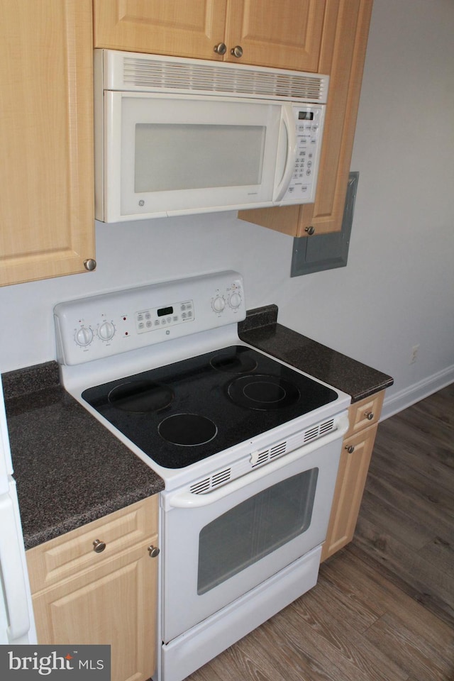 kitchen featuring light brown cabinets, dark stone countertops, white appliances, and dark wood-type flooring