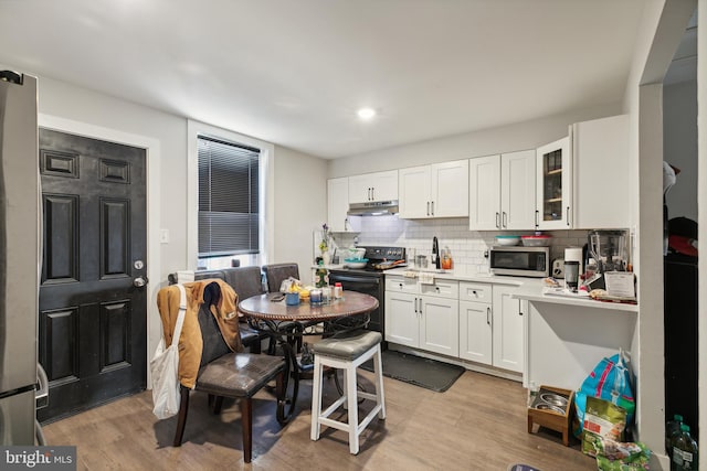 kitchen featuring white cabinetry, sink, stainless steel appliances, backsplash, and light wood-type flooring