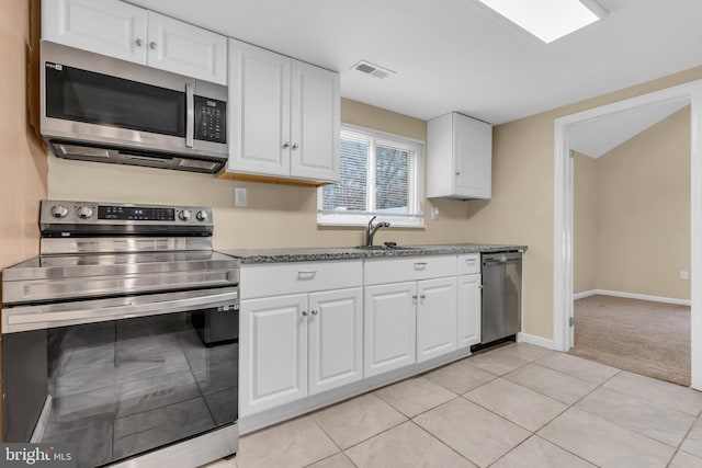 kitchen with light tile patterned flooring, sink, white cabinets, and stainless steel appliances