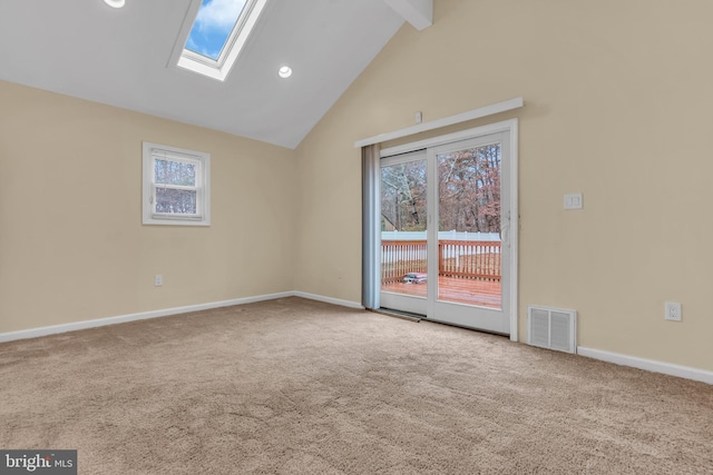 carpeted empty room with beamed ceiling, high vaulted ceiling, and a skylight