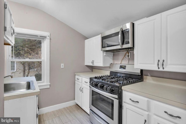 kitchen featuring white cabinets, sink, appliances with stainless steel finishes, and vaulted ceiling