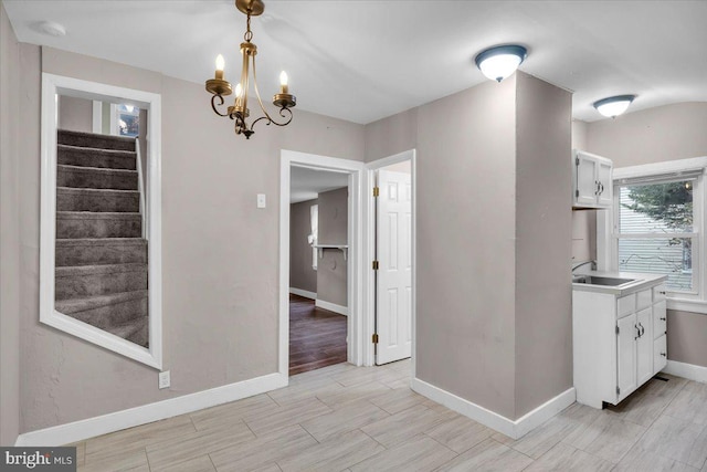 unfurnished dining area with light hardwood / wood-style flooring, a chandelier, and sink