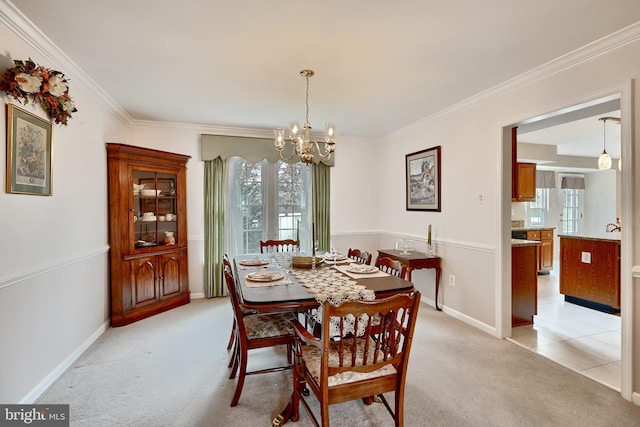 dining area with a chandelier, ornamental molding, light colored carpet, and a healthy amount of sunlight