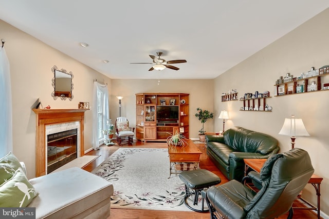 living room featuring hardwood / wood-style floors, ceiling fan, and a premium fireplace