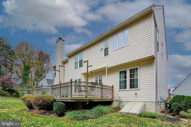 rear view of property featuring a lawn and a deck