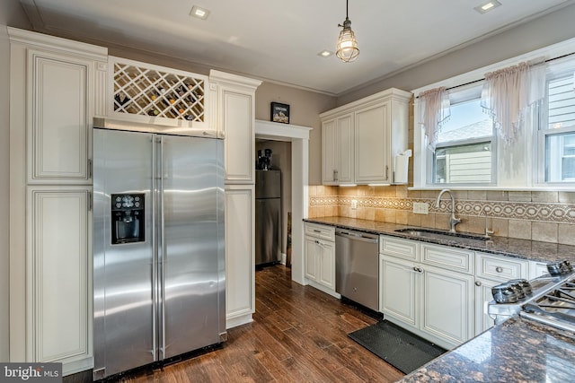 kitchen with pendant lighting, dark wood-type flooring, dark stone counters, sink, and stainless steel appliances