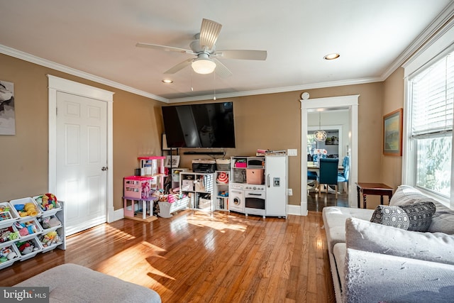 living room featuring ceiling fan, plenty of natural light, ornamental molding, and hardwood / wood-style flooring