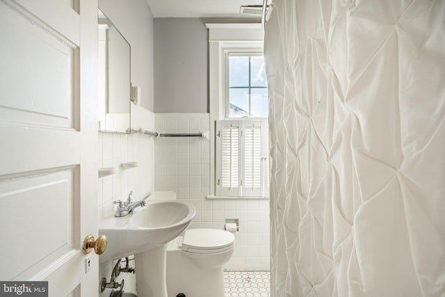 bathroom featuring tile patterned floors, a shower with curtain, tile walls, and toilet