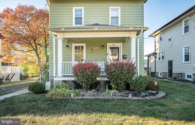 view of front property featuring covered porch and a front lawn