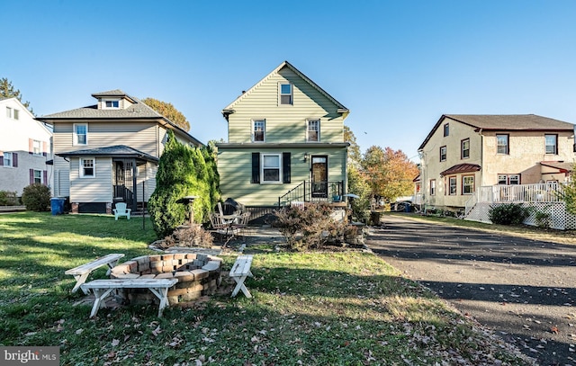 back of property with a lawn and a fire pit